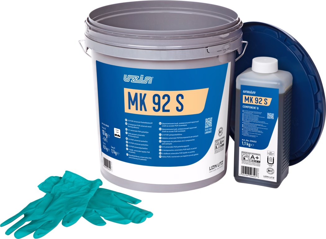 UZIN_Dummy_MK 92 S-10kg_2024-09 Studiofoto av et parkettlimsett: en stor grå plastbøtte med en tydelig blå etikett merket 'MK 92 S', til høyre en mindre rektangulær flaske merket 'MK 92 S Component B' med hvit kork, og et mørkeblått lokk lent bak. Foran ligger et par turkise engangshansker. Gjenstandene er plassert på hvit bakgrunn med jevn belysning, og framhever emballasjedetaljer og produktinformasjon for gulvlegging.